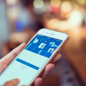 woman hand holding and pressing the Facebook screen